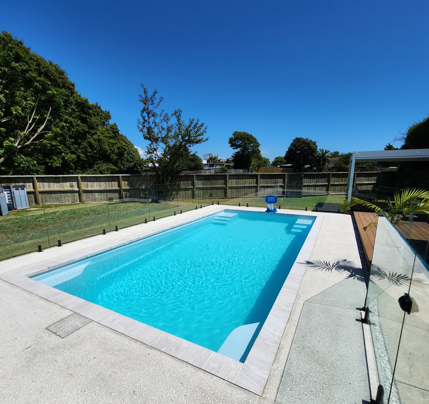 White Knight fibreglass pool in a fenced New Zealand backyard with pale blue water